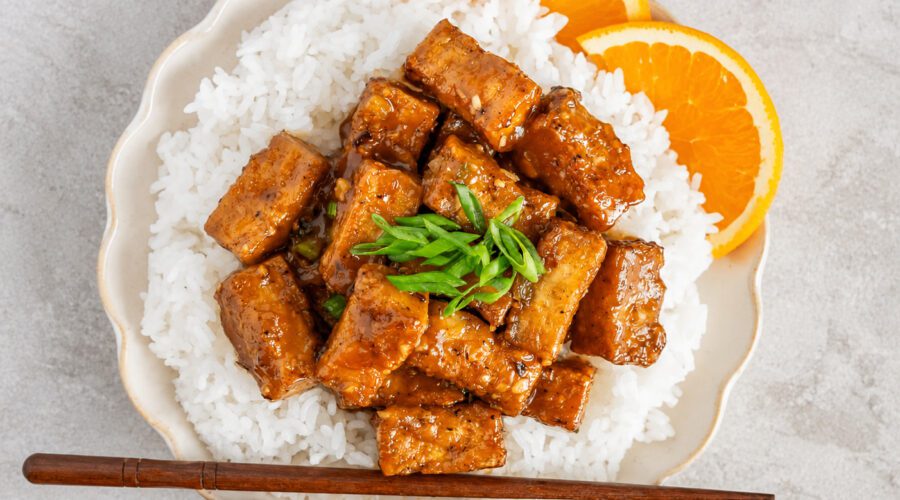 Crispy orange tofu coated in a sweet and sticky homemade orange sauce served over rice with green onions and sesame seeds.