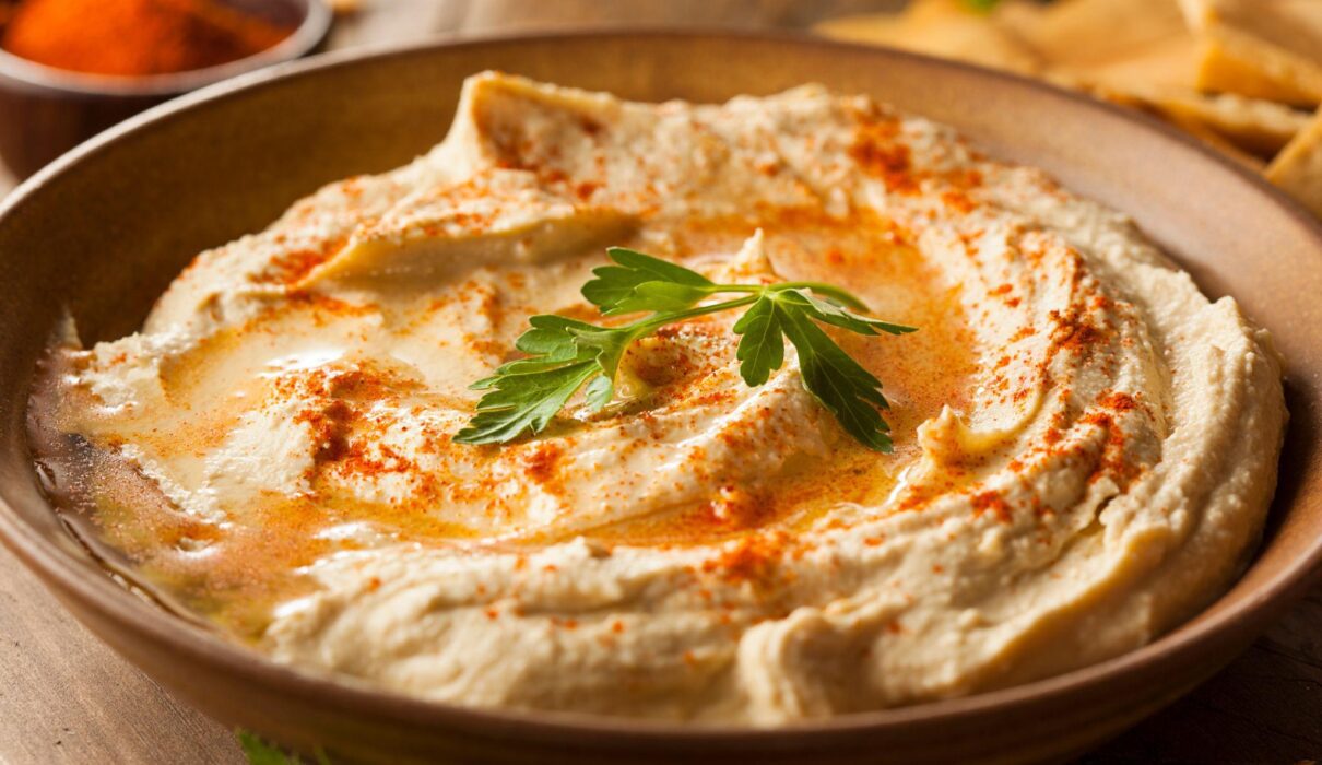 Low Sodium Hummus Recipe in a bowl topped with paprika and parsley, served with fresh vegetables and pita bread