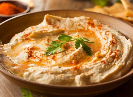 Low Sodium Hummus Recipe in a bowl topped with paprika and parsley, served with fresh vegetables and pita bread
