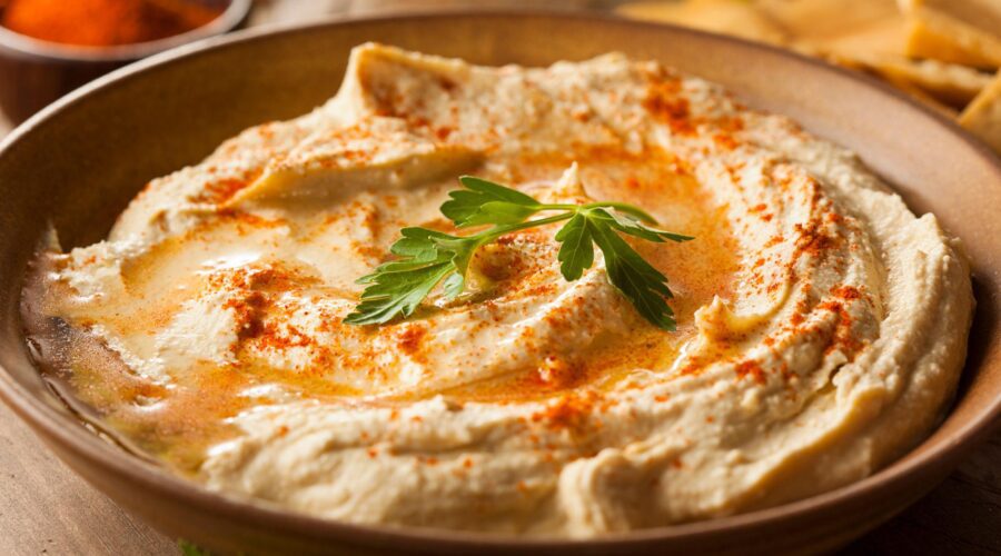 Low Sodium Hummus Recipe in a bowl topped with paprika and parsley, served with fresh vegetables and pita bread