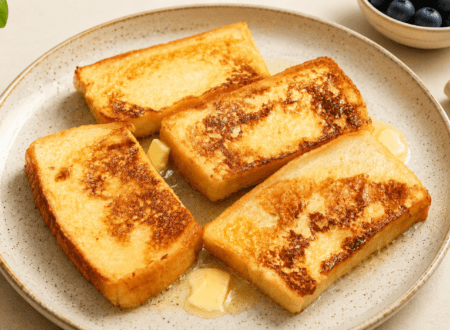Vegan French toast served with fresh berries, maple syrup, and a golden crispy exterior.