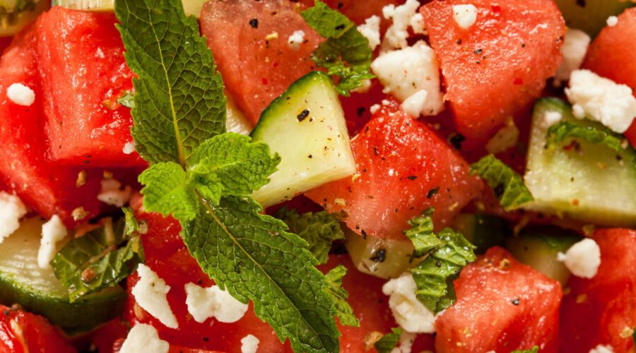 Fresh watermelon feta salad with mint leaves, vegan feta cheese, and lime dressing served in a bowl.