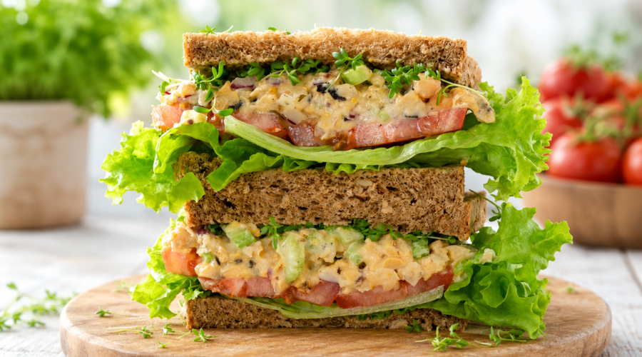 Vegan tuna sandwich made with mashed chickpeas, vegan mayonnaise, celery, and lettuce on whole grain bread.