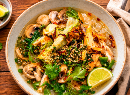 Bowl of vegan brothy rice with vegetables, herbs, and a flavorful savory broth.