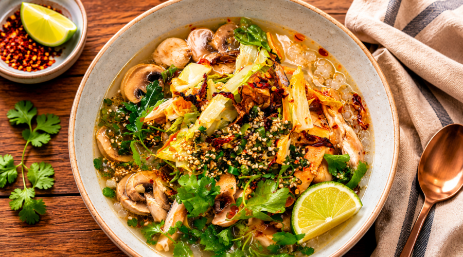 Bowl of vegan brothy rice with vegetables, herbs, and a flavorful savory broth.
