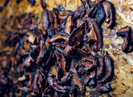 Crispy shiitake bacon strips on a plate with smoky seasoning and fresh herbs.