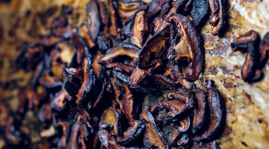 Crispy shiitake bacon strips on a plate with smoky seasoning and fresh herbs.