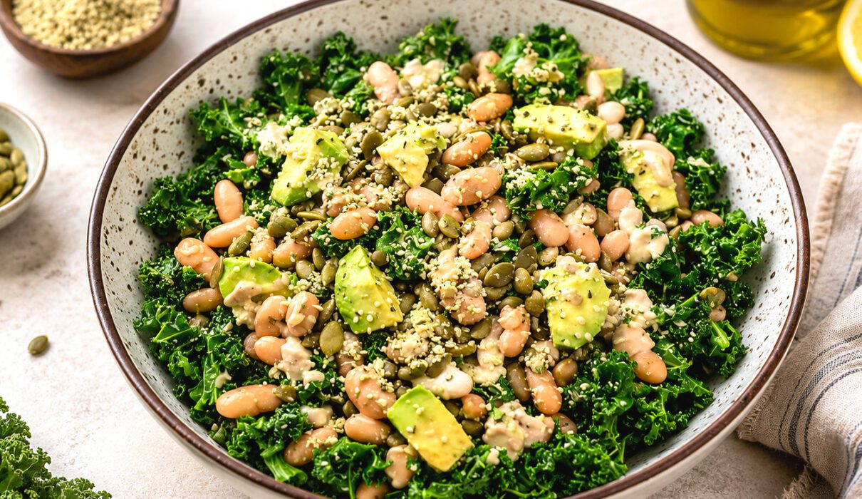 White bean kale salad with cherry tomatoes, cucumber, red onion, and lemon dressing served in a large bowl.