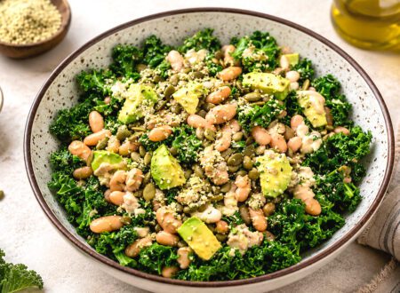 White bean kale salad with cherry tomatoes, cucumber, red onion, and lemon dressing served in a large bowl.