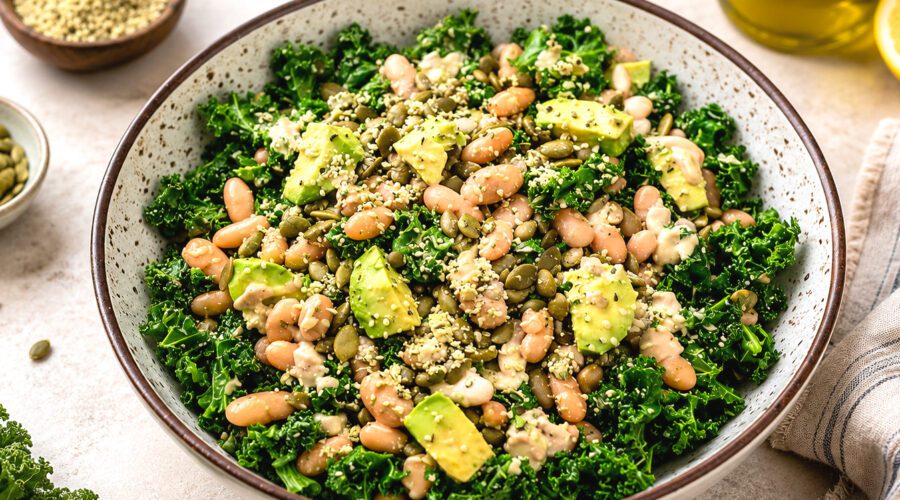 White bean kale salad with cherry tomatoes, cucumber, red onion, and lemon dressing served in a large bowl.
