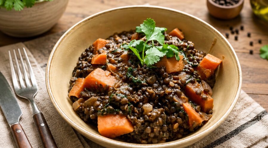 Bowl of cooked beluga lentils with vegetables, herbs, and seasonings served as a healthy vegan meal.