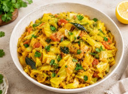 Bowl of easy cabbage curry with tomatoes and spices, garnished with fresh cilantro and served with rice.