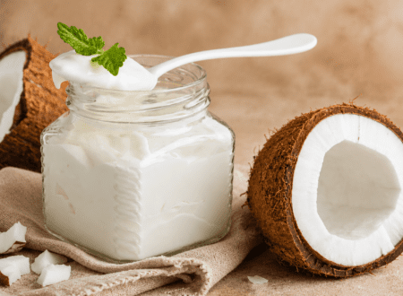 Creamy homemade coconut milk yogurt served in a glass jar with fresh fruit on top.