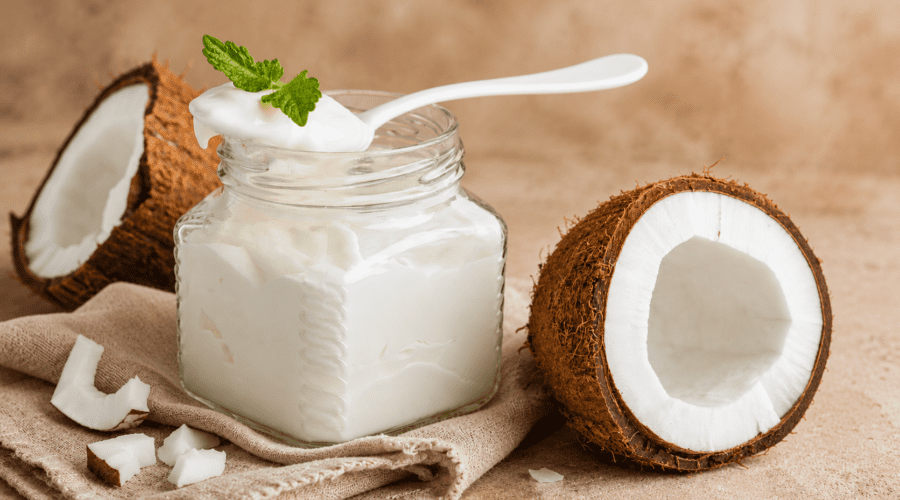 Creamy homemade coconut milk yogurt served in a glass jar with fresh fruit on top.