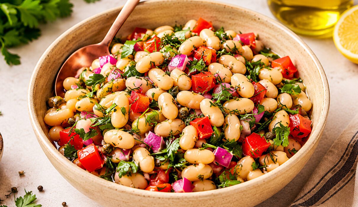 Bowl of Tuscan white beans cooked with garlic, herbs, tomatoes, and fresh parsley.