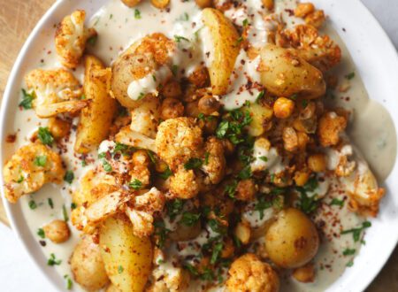 Roasted cauliflower, chickpeas, and potatoes served in a bowl with creamy tahini sauce and fresh herbs.