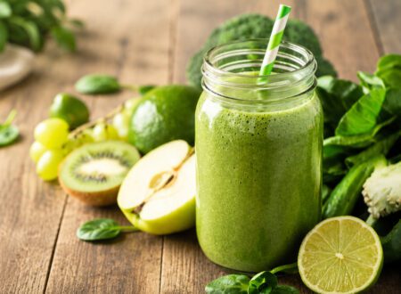 Healthy spirulina smoothie in a glass with vibrant green color and fresh fruit nearby.