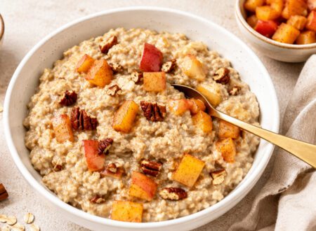 Bowl of warm vegan stewed apples with cinnamon sticks and diced apples served over oatmeal.
